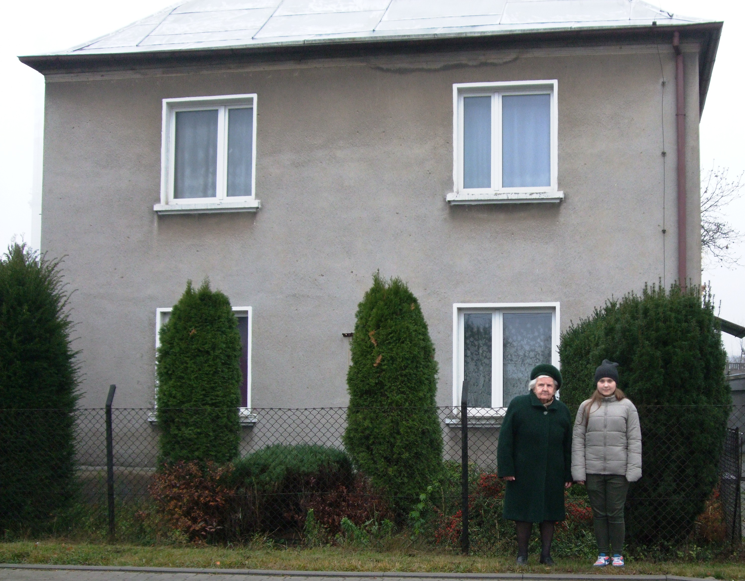 Marta Pilśniak z prawnuczką Klaudią na tle domu, z którego wysiedlono rodzinę. Zdjęcie z 2015 r.